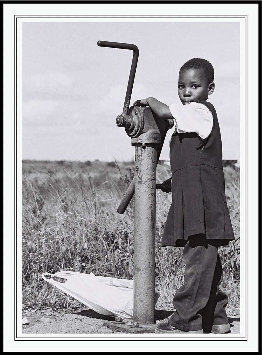 A boy fetching water from a hand pump