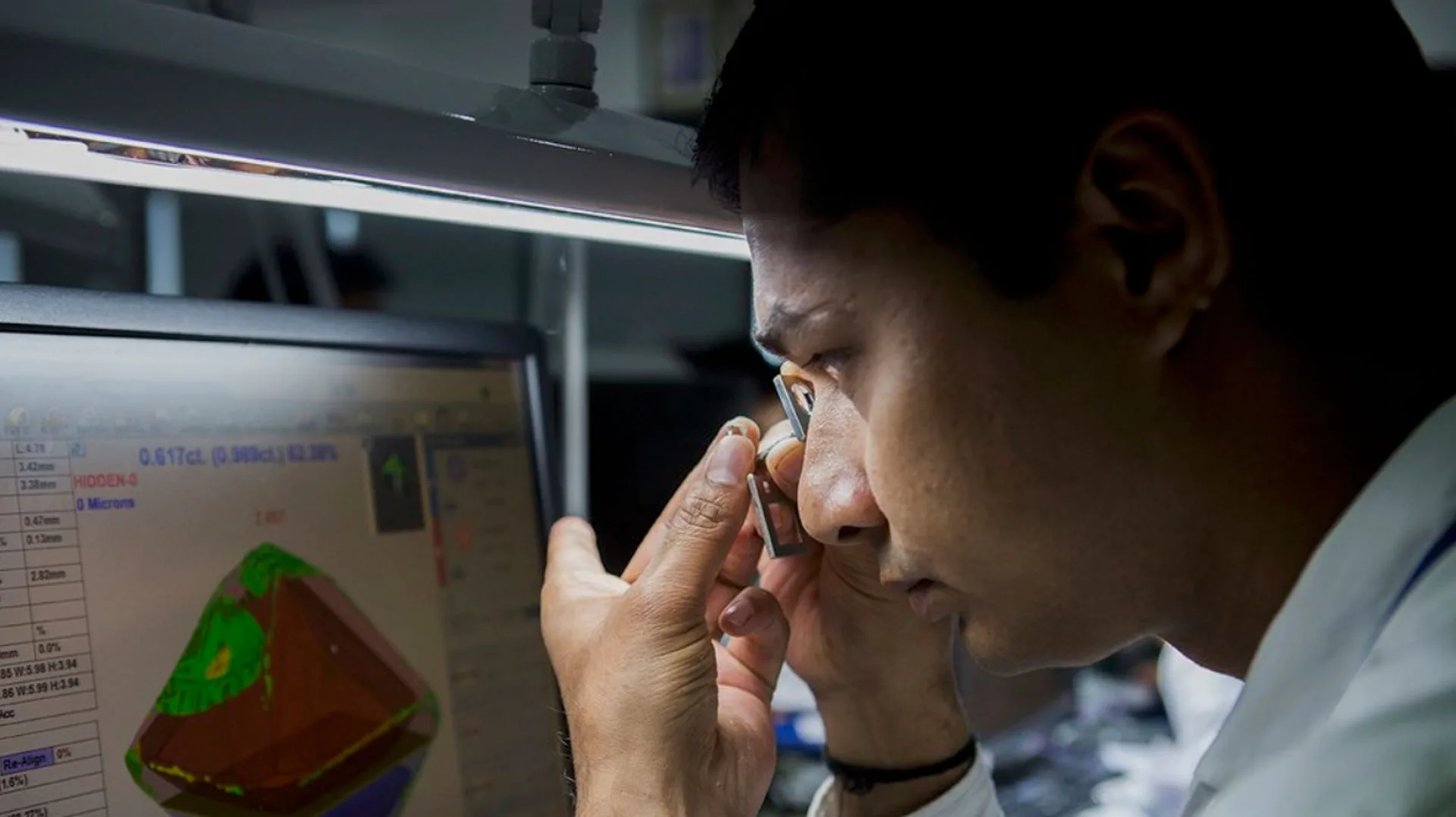 A gemologist inspecting a polished diamond through a loupe